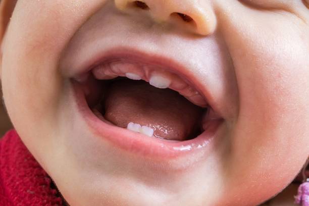 A smiling baby with the first two lower teeth showing.